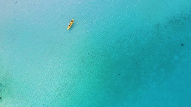 Kayak on turquoise tropical sea water during warm summer vacation holidays at beach, quiet activity in family, aerial top down view from drone, beautiful abstract video background for copy paste