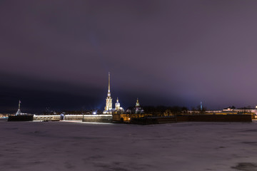 Fototapeta na wymiar Peter and Paul Fortress of St. Petersburg, Russia in the evening or in the night and Neva river covered with the ice and snow in the cloudy weather