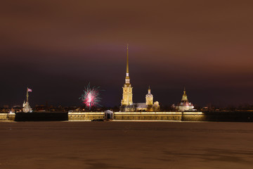 Obraz premium Peter and Paul Fortress of St. Petersburg, Russia in the evening or in the night and Neva river covered with the ice and snow in the cloudy weather an with the fireworks in the sky
