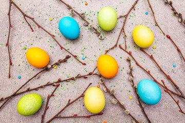 Fototapeta na wymiar Easter eggs concept willow seals branches, sweet topping on a stone background wallpaper, top view.