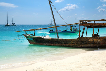 Fototapeta na wymiar Wooden traditional ship on paradise sandy beach of Zanzibar island Indian ocean