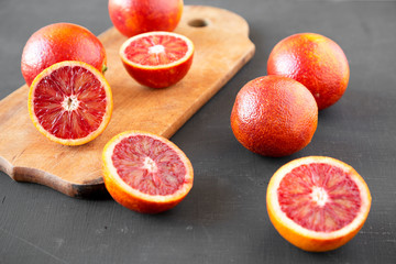 Whole and halved blood oranges on black background, low angle view. Close-up.