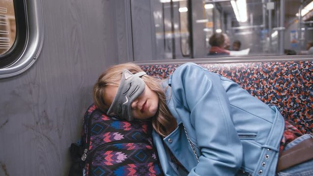 Slow Motion Young beautiful girl in the Blindfold on the eyes, fell asleep on the subway train. Head put on a backpack. The train arrives at the station. The concept of fatigue, desire to sleep.