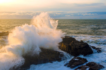 Fototapeta na wymiar Seascape. Waves of the Atlantic Ocean crashing against a rock at sunset. Portugal