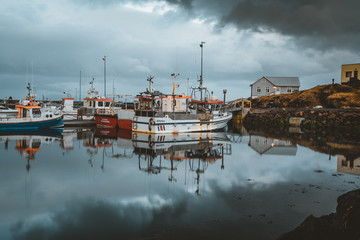 Fototapeta na wymiar Grundarfjordur, Iceland - 03 January 2019: Harbor with motionless boats during the twilight of the afternoon, Kirkjufell volcanic mountain in the background