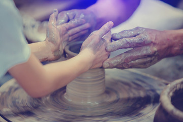 close-up to hands of potter teacher and child