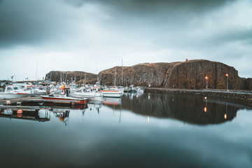 Grundarfjordur, Iceland - 03 January 2019: Harbor with motionless boats during the twilight of the afternoon, Kirkjufell volcanic mountain in the background