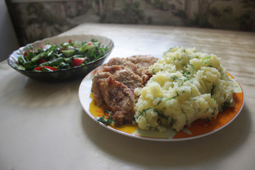 Dish consisting of fried meat and boiled potatoes and cucumber salad with green onions and tomatoes.