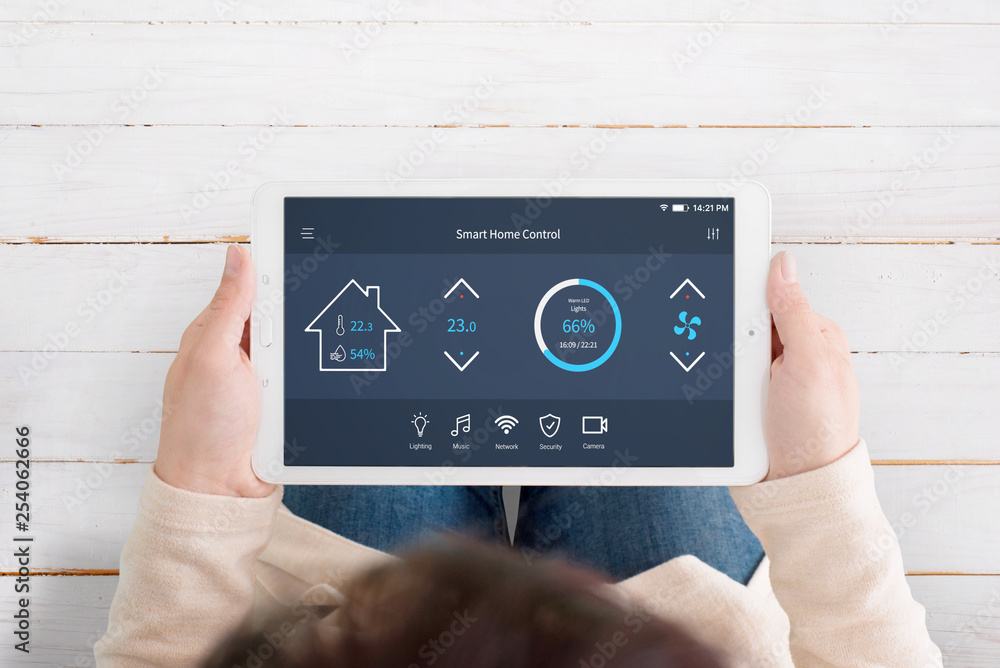 Poster Modern, automated home control app with artificial intelligence on tablet display in woman hands. Top view. Wooden floor in background.
