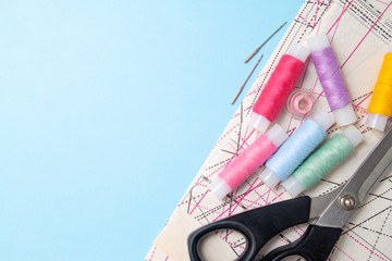 Multicolored thread coils and measuring tape on blue background. Sewing supplies scissors,, pattern...