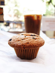 Chocolate Chip Muffin or cupcake and Iced coffee in plastic takeaway cup from cafe or bakery in Williamsburg, Brooklyn, New York City, close up with selective focus and blurry backgroud