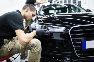 Car detailing - Worker with orbital polisher in auto repair shop.