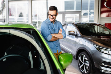 Fototapeta na wymiar Young handsome man choosing a new car at car showroom.