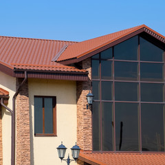 building with yellow walls and a red-brown roof. Modern materials of finish and roofing.