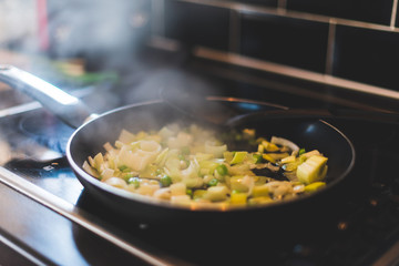 Leeks and other vegetables are being cooked in a frying pan