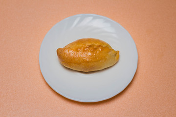 Fresh patties with meat, cabbage or any filling. Baked pies in the oven. On a white plate.