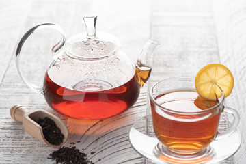 Transparent teapot with red (black) tea on the table