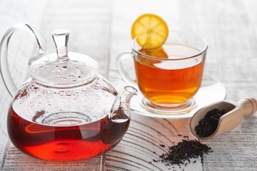 Transparent teapot with red (black) tea on the table