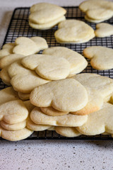 Fototapeta na wymiar Stacks of heart shaped sugar cookies on a black wire cooling rack, granite kitchen counter