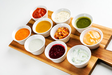 Bowls with sauces on wooden tray