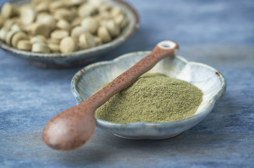 Bio Green BARLEY GRASS powder and tablets. Concept for a healthy dietary supplementation. Rustic wooden background. Copy space. 