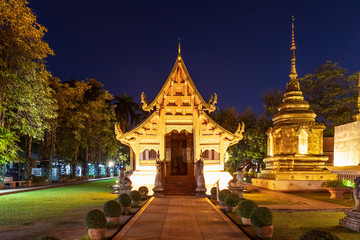Chapel and golden pagoda at Wat Phra Singh Woramahawihan in Chiang Mai at twilight or night with stars in sky