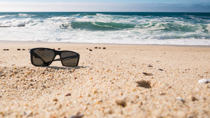 Sunglasses on beach, sunny summer day. Copy space on right.