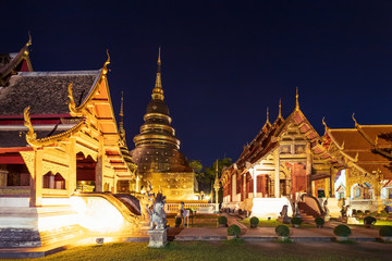 Fototapeta premium Chapel and golden pagoda at Wat Phra Singh Woramahawihan in Chiang Mai at twilight or night with stars in sky