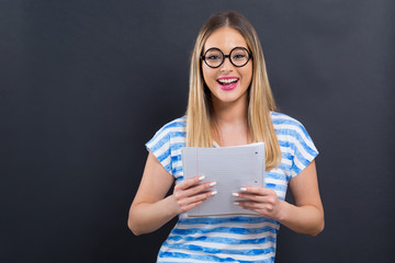 Young woman with notebook and pencil on a black background