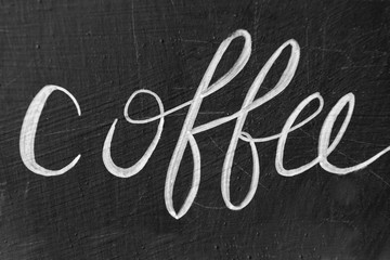 Coffee word handwritten with chalk on blackboard, coffee shop sign