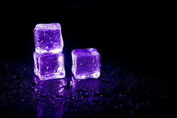 Purple ice cubes reflection on black table background.