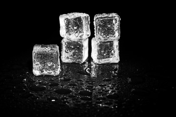 ice cubes reflection on black table background.