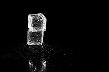 ice cubes reflection on black table background.