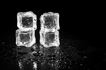 ice cubes reflection on black table background.