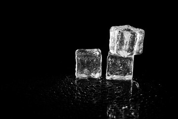 ice cubes reflection on black table background.