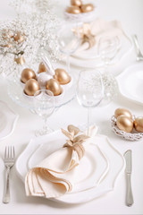 Obraz na płótnie Canvas Happy Easter! Golden decor and table setting of the Easter table with white dishes of white color.