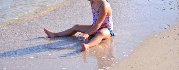 the girl is sitting on the beach and playing in the water