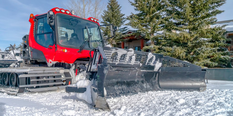 Red snow groomer on a sunlit snow covered ground