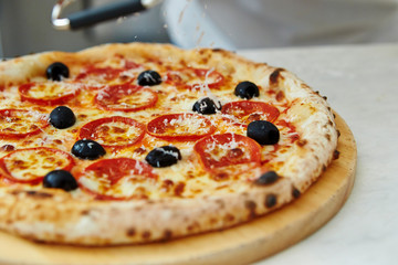 Grating cheese on pepperoni pizza 