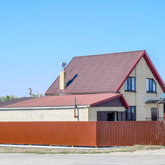 House with plastic windows and roof of corrugated sheet. Roofing of metal profile wavy shape on the house with plastic windows
