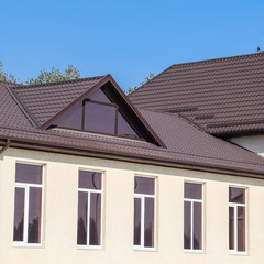 House with plastic windows and roof of corrugated sheet. Roofing of metal profile wavy shape on the house with plastic windows