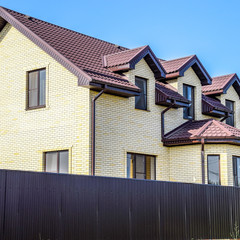 The house with plastic windows and a roof of corrugated sheet. Roofing of metal profile wavy shape on the house with plastic windows