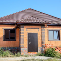 The house with plastic windows and a roof of corrugated sheet. Roofing of metal profile wavy shape on the house with plastic windows