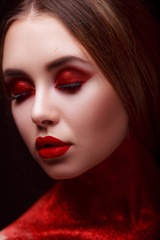 Red makeup in the style of beauty. Bright lips and eyes. Portrait of a beautiful young girl. Journal detailed skin retouching. Expressive eyebrows. Huge eyelashes. Neon shadows.