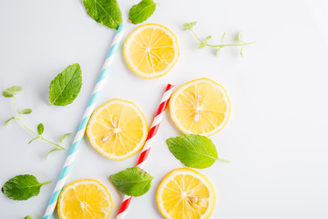 Colorful drinking paper straws and mint leaves, lemon slices on a white background