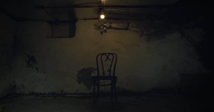 A single chair sits in the middle of a dark creepy cellar.
