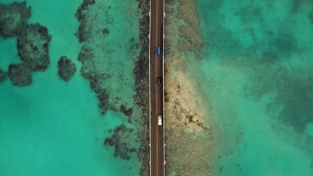 Birds eye view following car bridge over turquoise water on tropical island. MOVING FORWARD.