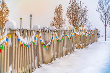 Snowy wooden fence lined with colorful lights