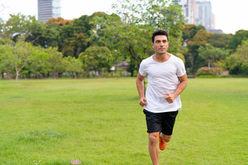 Young handsome Hispanic man jogging at the park