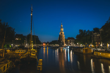 Fototapeta na wymiar Amsterdam clock tower, canal, house boats, and night lights